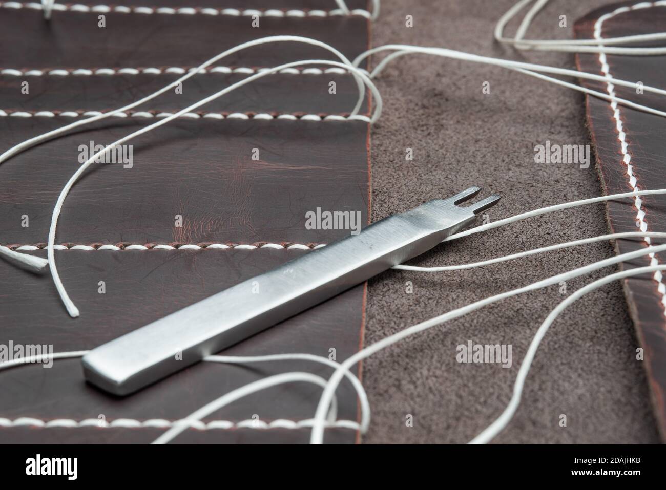 punzone per prodotti in pelle giacente su un materiale con bianco filettature Foto Stock