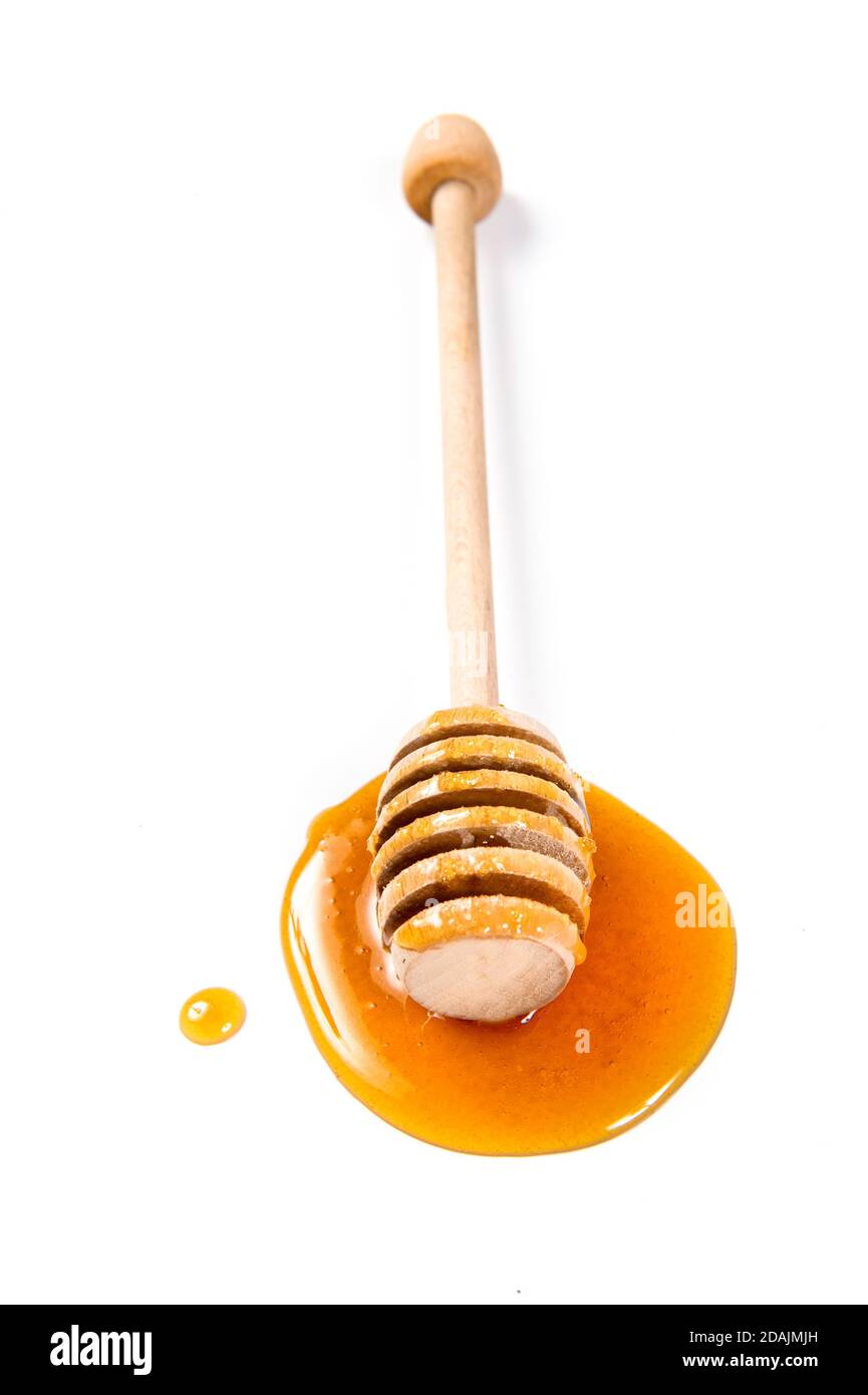 cucchiaia di miele di legno con miele gocciolante su sfondo bianco Foto Stock