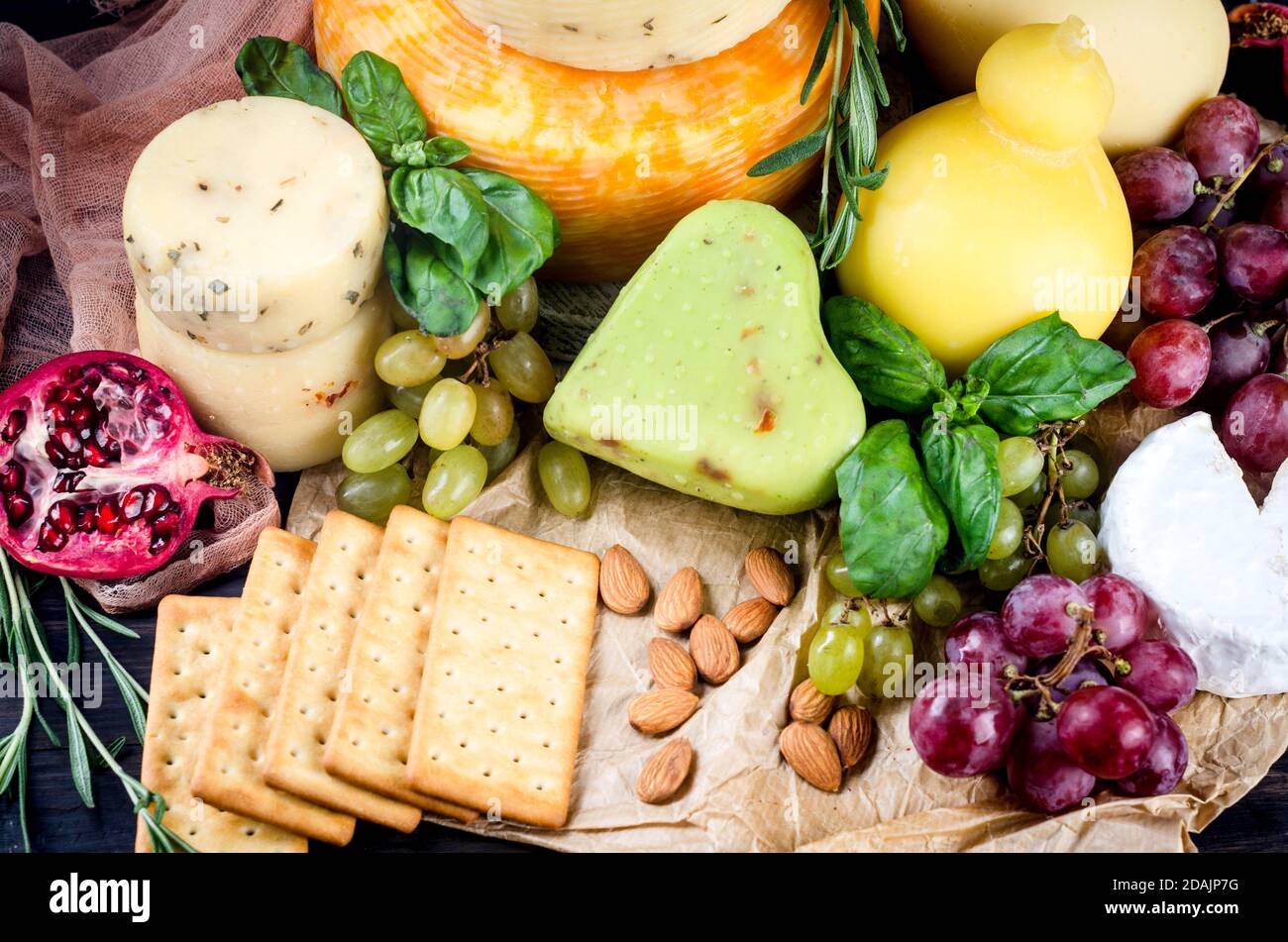 Un mucchio di teste di formaggio, verdure, frutta, biscotti e noci sul tavolo Foto Stock