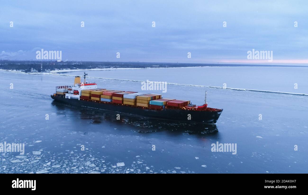 Volo aereo della nave di carico che si muove attraverso il mare. In background paesaggio invernale. Foto Stock