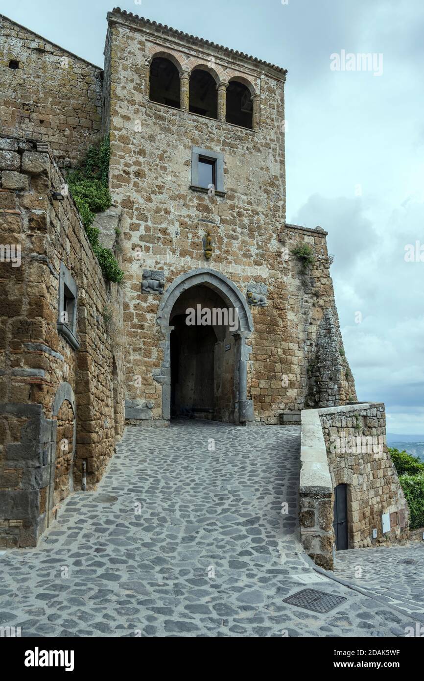 Paesaggio urbano con ingresso a s.Maria nello storico borgo collinare, girato in luminosa luce a Civita di Bagnoregio, Viterbo, Lazio, Italia Foto Stock