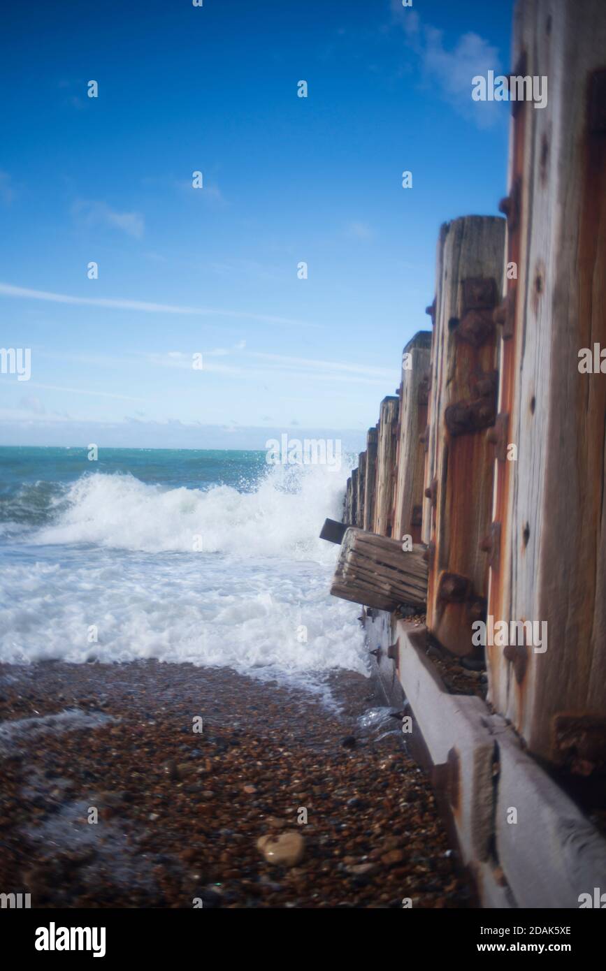 Frangiflutti sulla spiaggia di Hove, onde che infrangono, cielo blu. Foto Stock