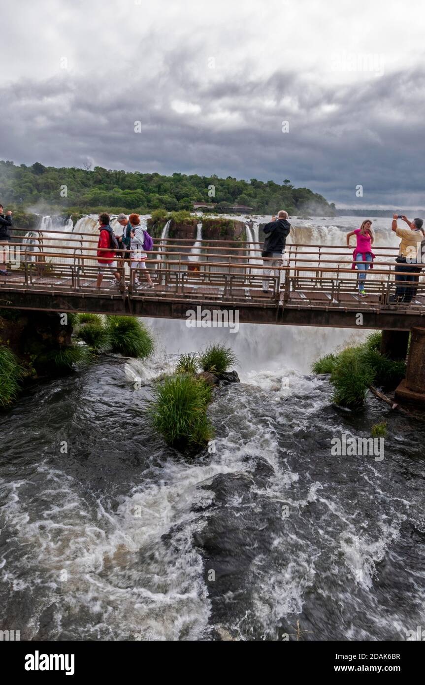I visitatori su un passaggio pedonale sopra il Diavolo alto 82 metri Le cascate di Gole sono la più grande cascata delle cascate di Iguazu All'interno del Parco Nazionale di Iguazu ON Foto Stock