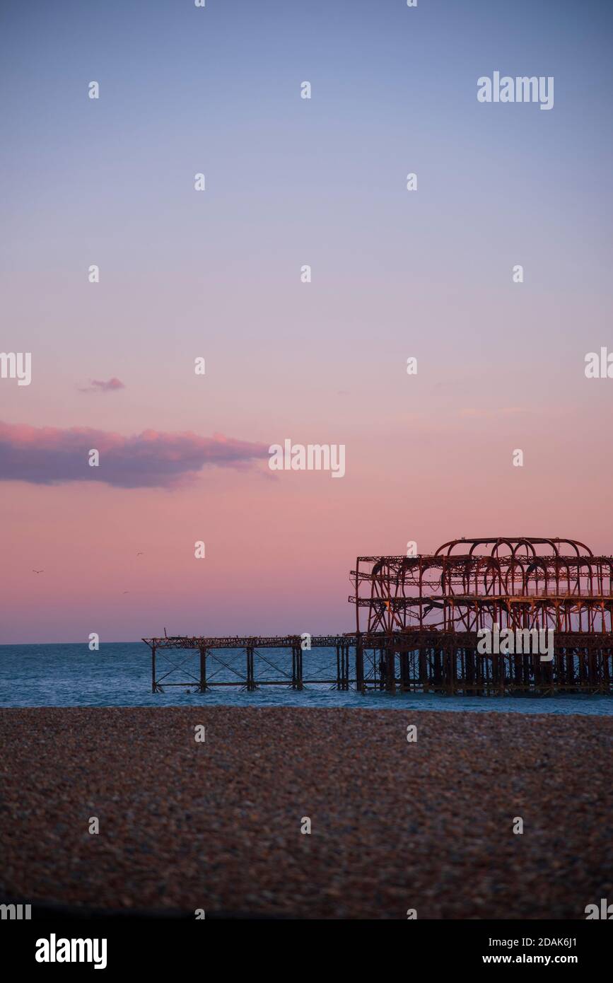Le iconiche rovine bruciate del West Pier di Brighton sul lungomare di Brighton al tramonto durante l'estate. Cielo rosso e una nuvola singola nel cielo. Brighton Regno Unito Foto Stock