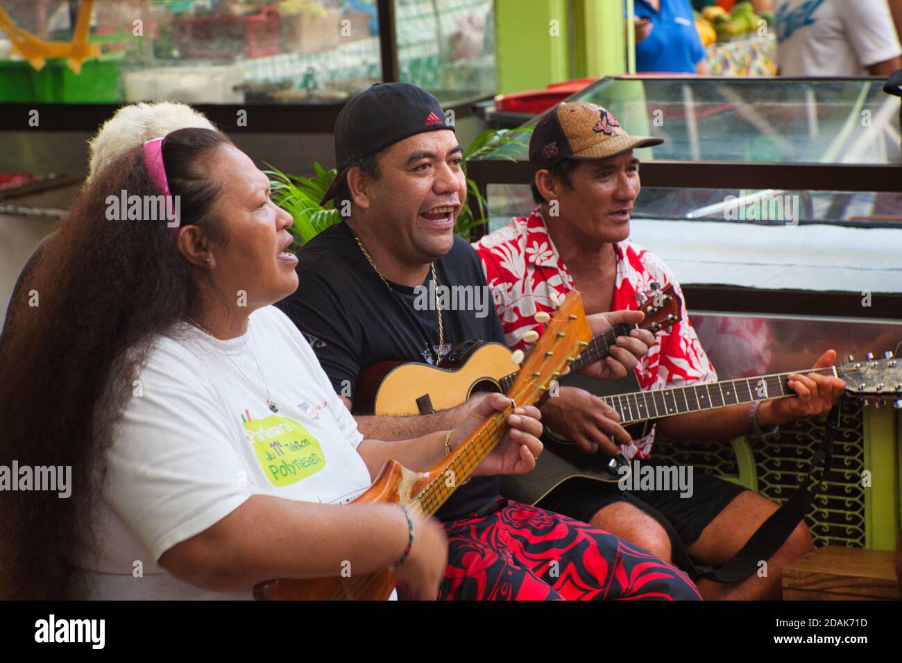 Due uomini e una donna con chitarra e ukulele suonano musica improvvisata e cantano in una strada a Papeete, Tahiti, Polinesia francese Foto Stock
