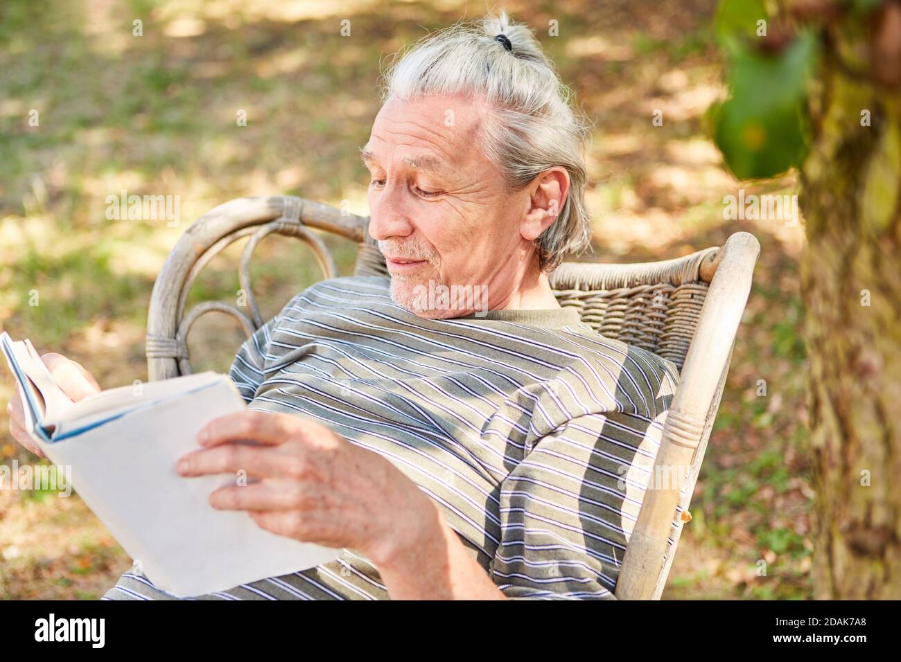 Anziani pensionati leggere un libro in giardino in estate per rilassarsi Foto Stock