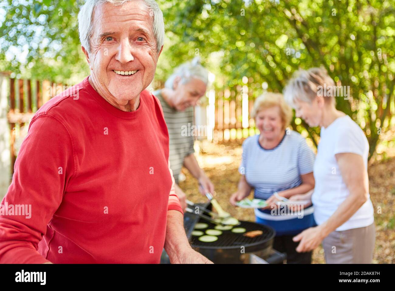 Sorridendo anziani pensionati con amici che hanno un barbecue insieme dentro il giardino Foto Stock