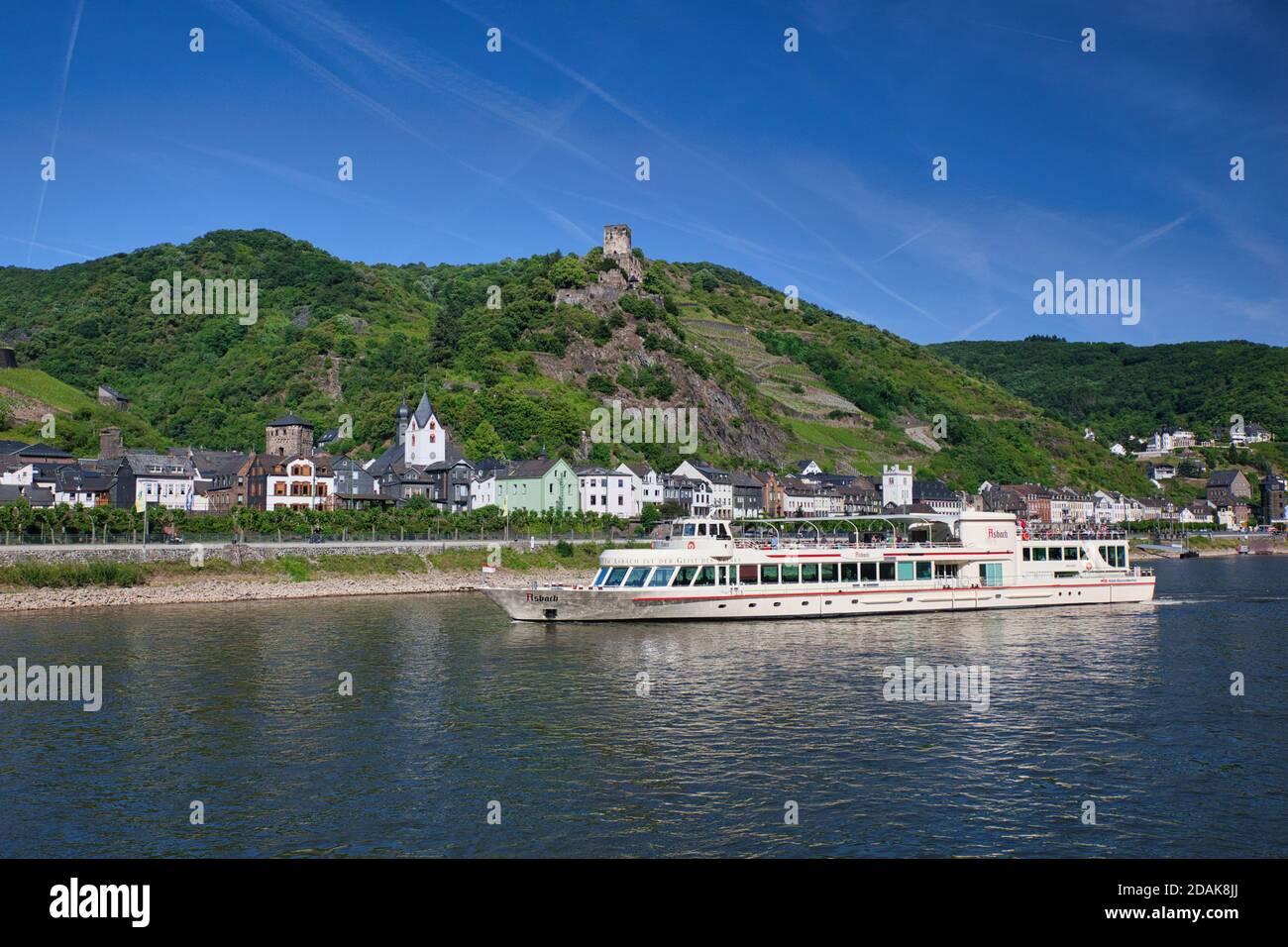 Una nave da crociera sul fiume Reno naviga lungo il fiume fino allo sfondo di una città con un castello in cima a una collina sulle colline circostanti. Sul fiume Reno, Germania Foto Stock