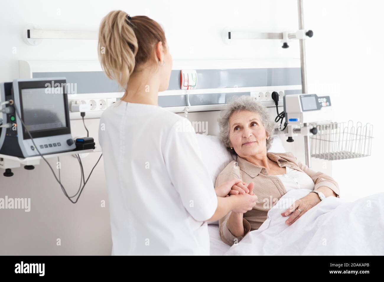 La donna con malattia di Alzheimer che si trova a letto riceve assistenza infermieristica. Cura e cura degli anziani affetti dalla malattia di Alzheimer Foto Stock