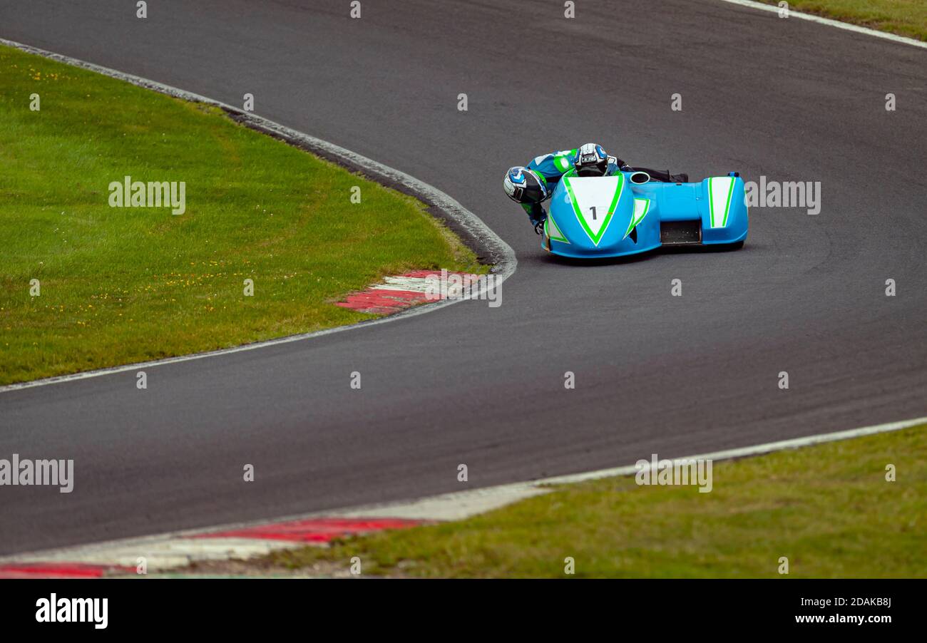 Una panoramica di un sidecar da corsa mentre si curva su una pista. Foto Stock