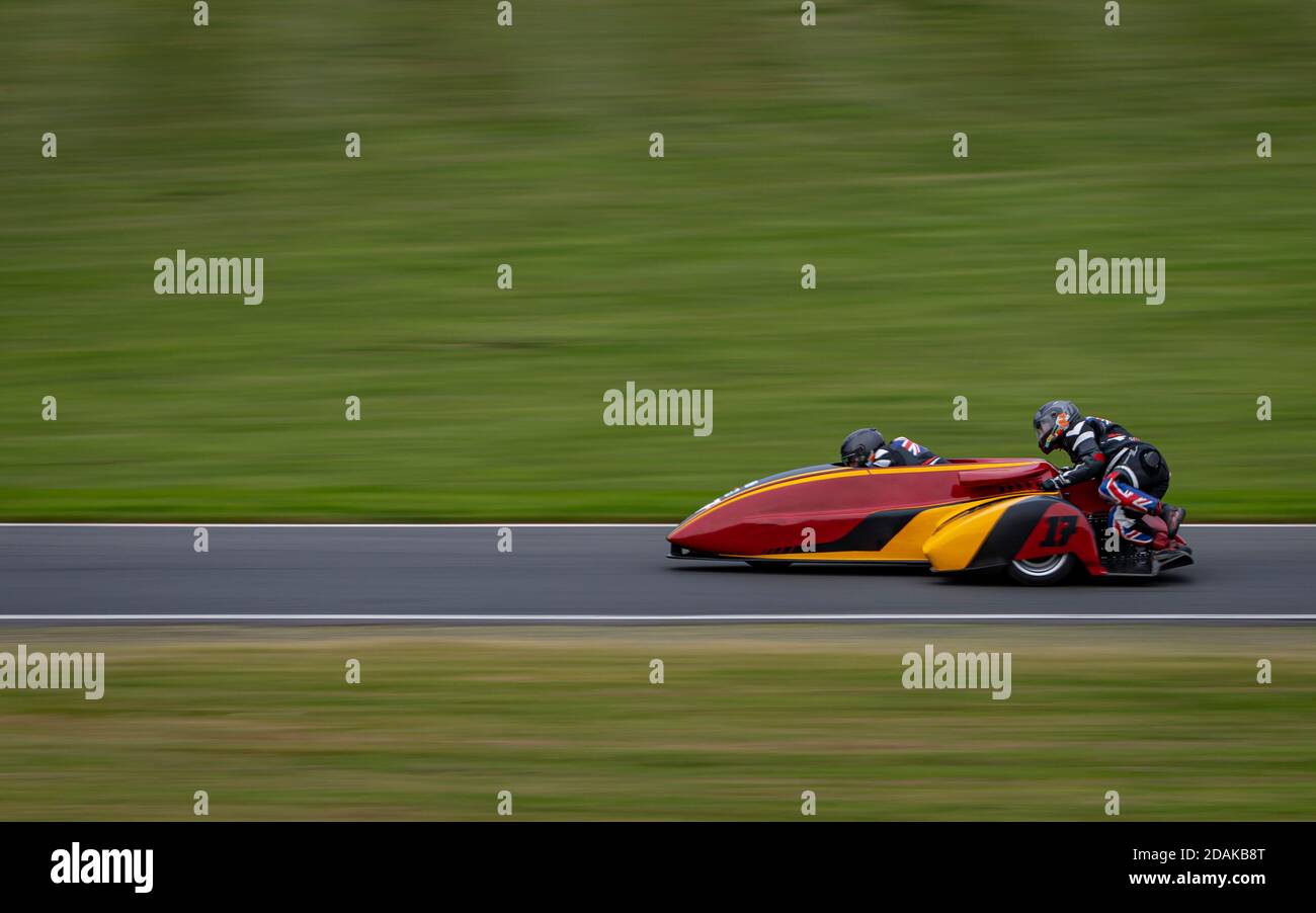 Una panoramica di un sidecar da corsa mentre si curva su una pista. Foto Stock