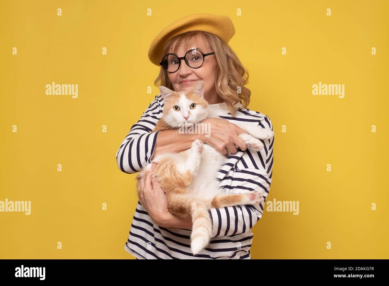 Donna caucasica matura con occhiali che tengono un gatto Foto Stock