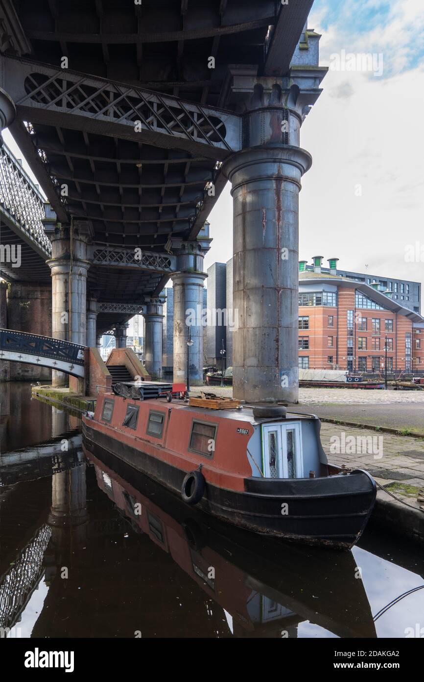 Una chiatta di canale ormeggiata sotto i vecchi ponti ferroviari, castlefield canale bacino, Manchester Foto Stock