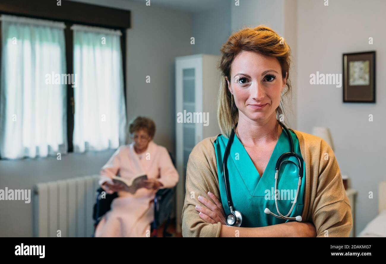 Bella femmina medico in posa di una clinica geriatrica Foto Stock