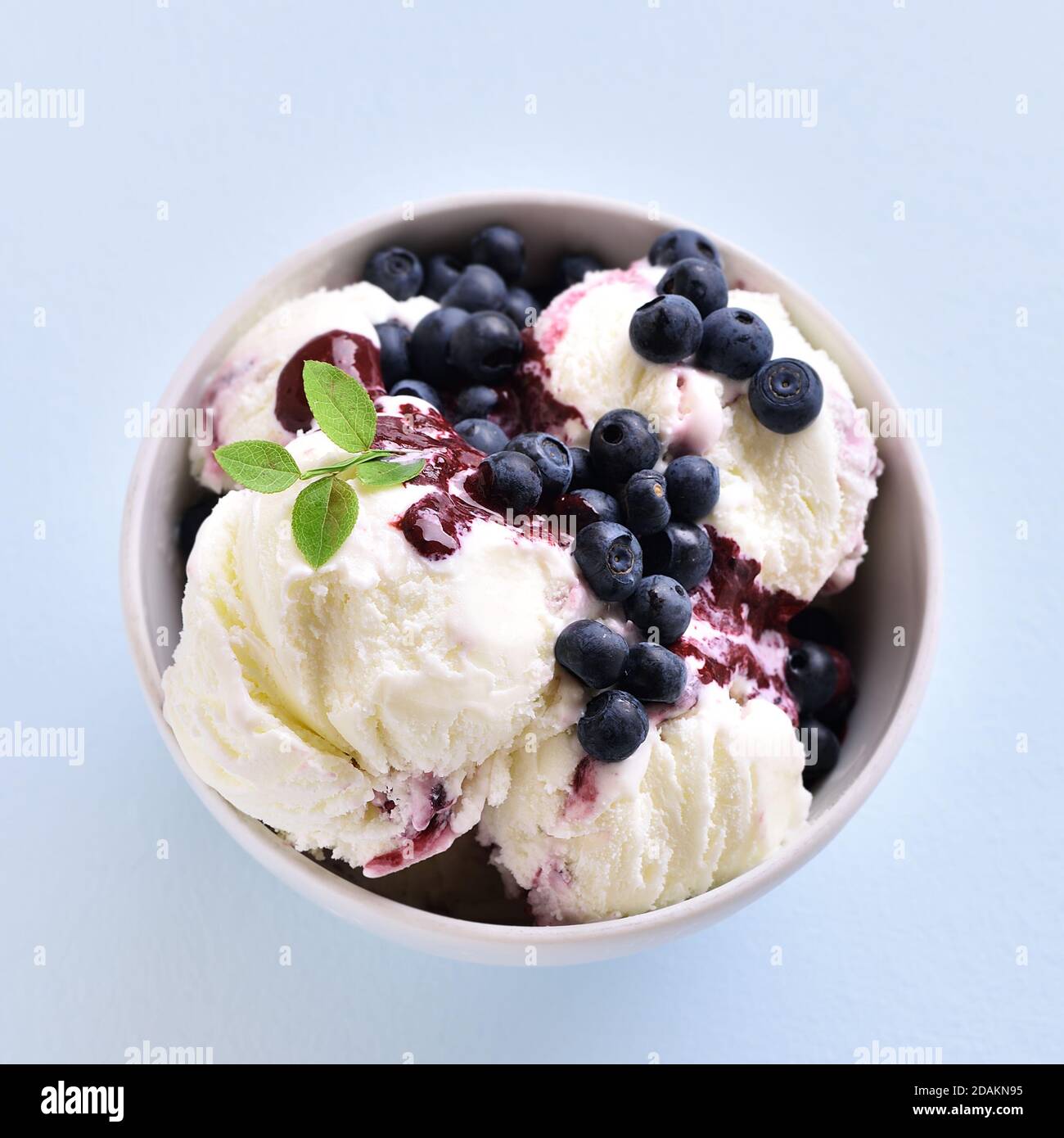 Vista ravvicinata del gelato al mirtillo nella ciotola su sfondo blu. Foto Stock