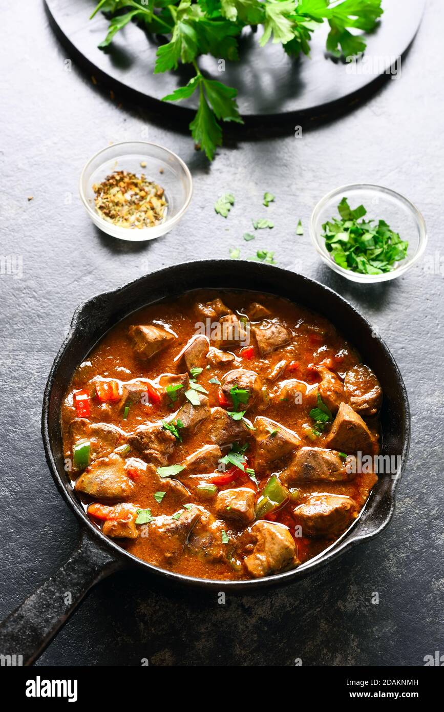 Fegato di pollo peri-peri in padella su fondo di pietra scuro. Foto Stock