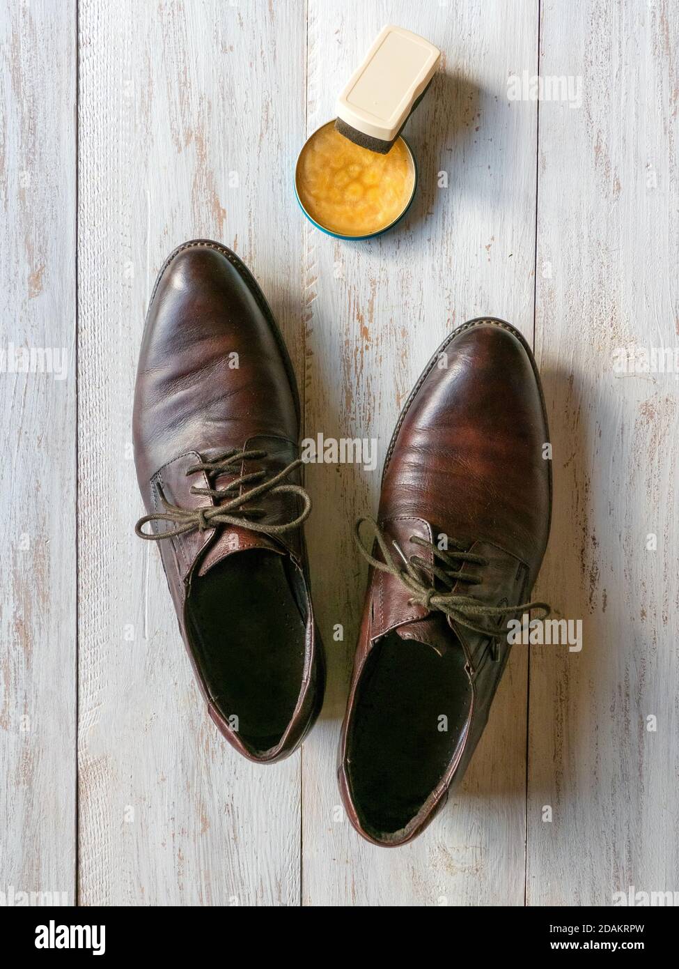 Cera protettiva per scarpe in pelle. Concetto di cura delle scarpe. Un paio di stivali classici sul pavimento in legno. Foto Stock