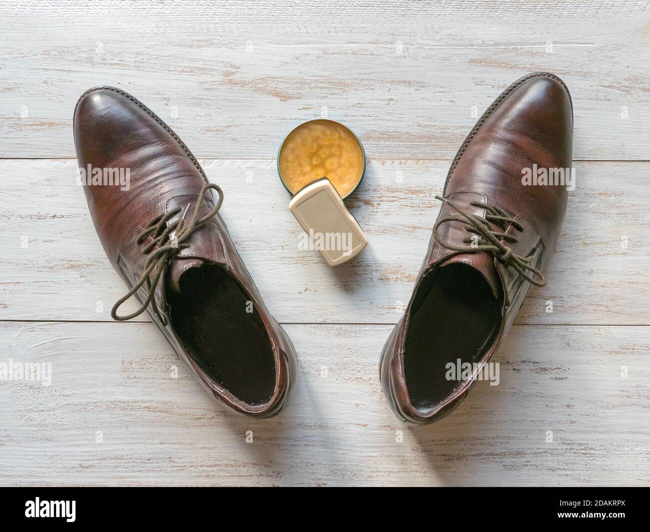 Cera protettiva per scarpe in pelle. Concetto di cura delle scarpe. Un paio di stivali classici sul pavimento in legno. Foto Stock