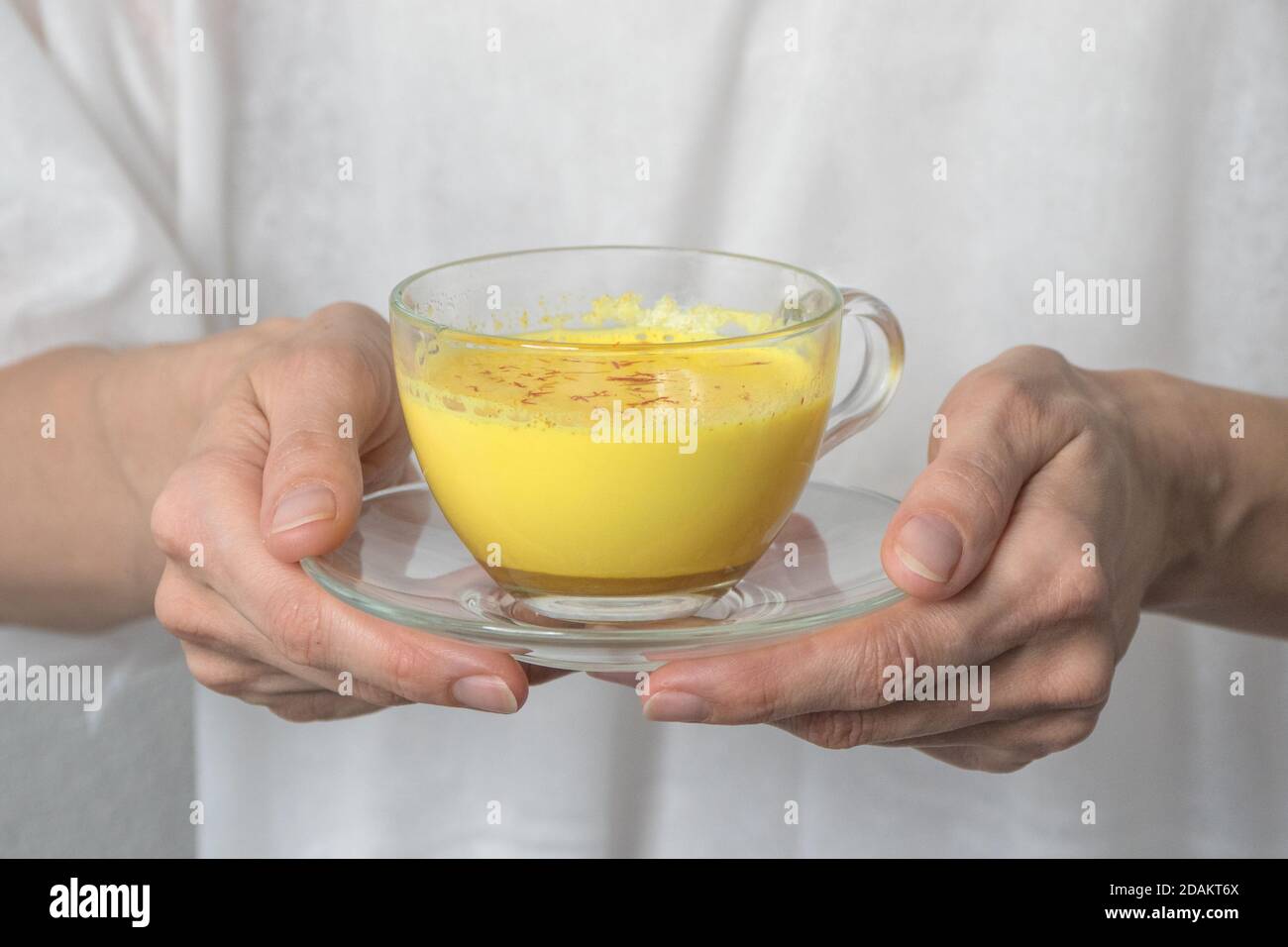 Sano latte curcuma vegano in una mano. Un rimedio per i virus e molte malattie. Concetto di medicina alternativa. Foto Stock