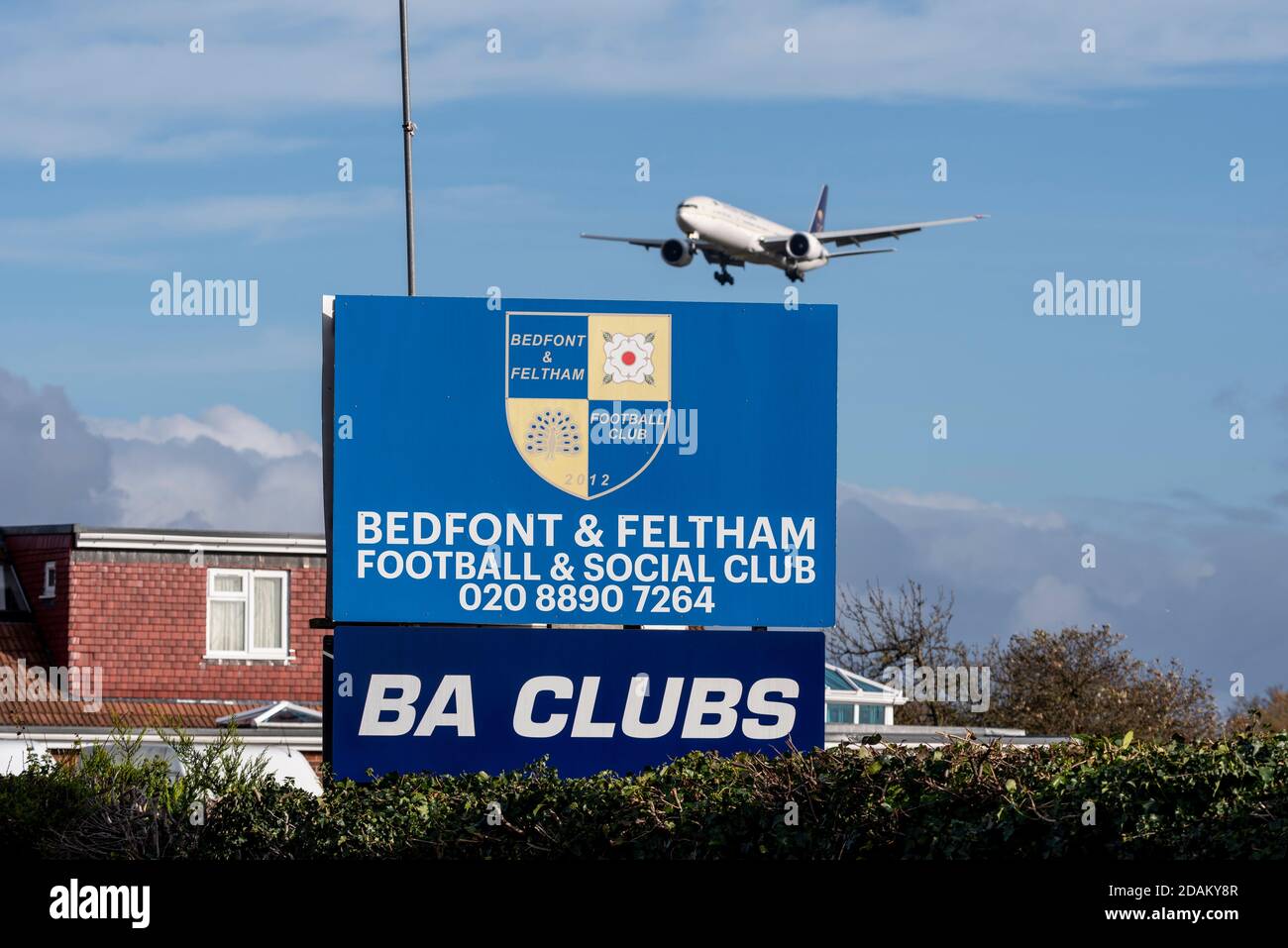 Aereo jet Airliner in avvicinamento per atterrare all'aeroporto Heathrow di Londra, Regno Unito, oltre Bedfont & Feltham Football & Social Club. BA Club. Basso sopra casa Foto Stock