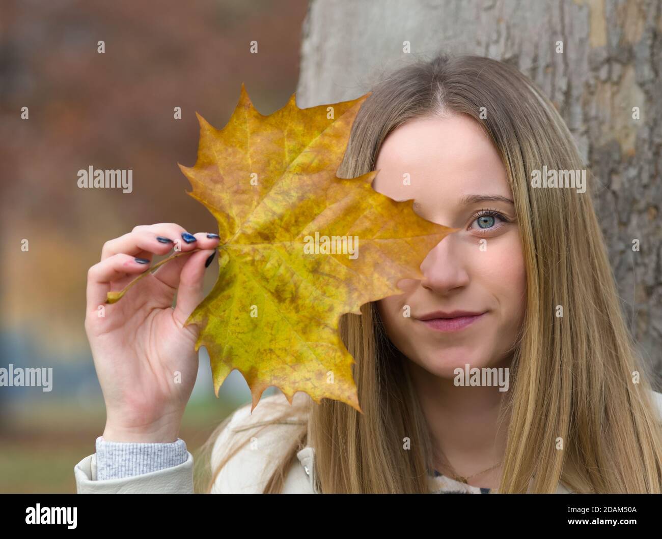 Ritratto di una giovane bella donna bionda nel Parco d'autunno Con foglia d'acero Foto Stock