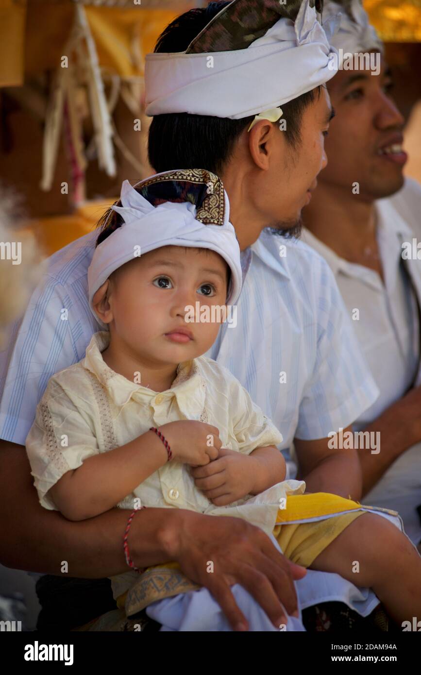 Ragazzo e padre balinese in abbigliamento tradizionale frequentando un tempio locale per l'inizio del festival di Galungan. Vicino a Ubud, Bali, Indonesia Foto Stock