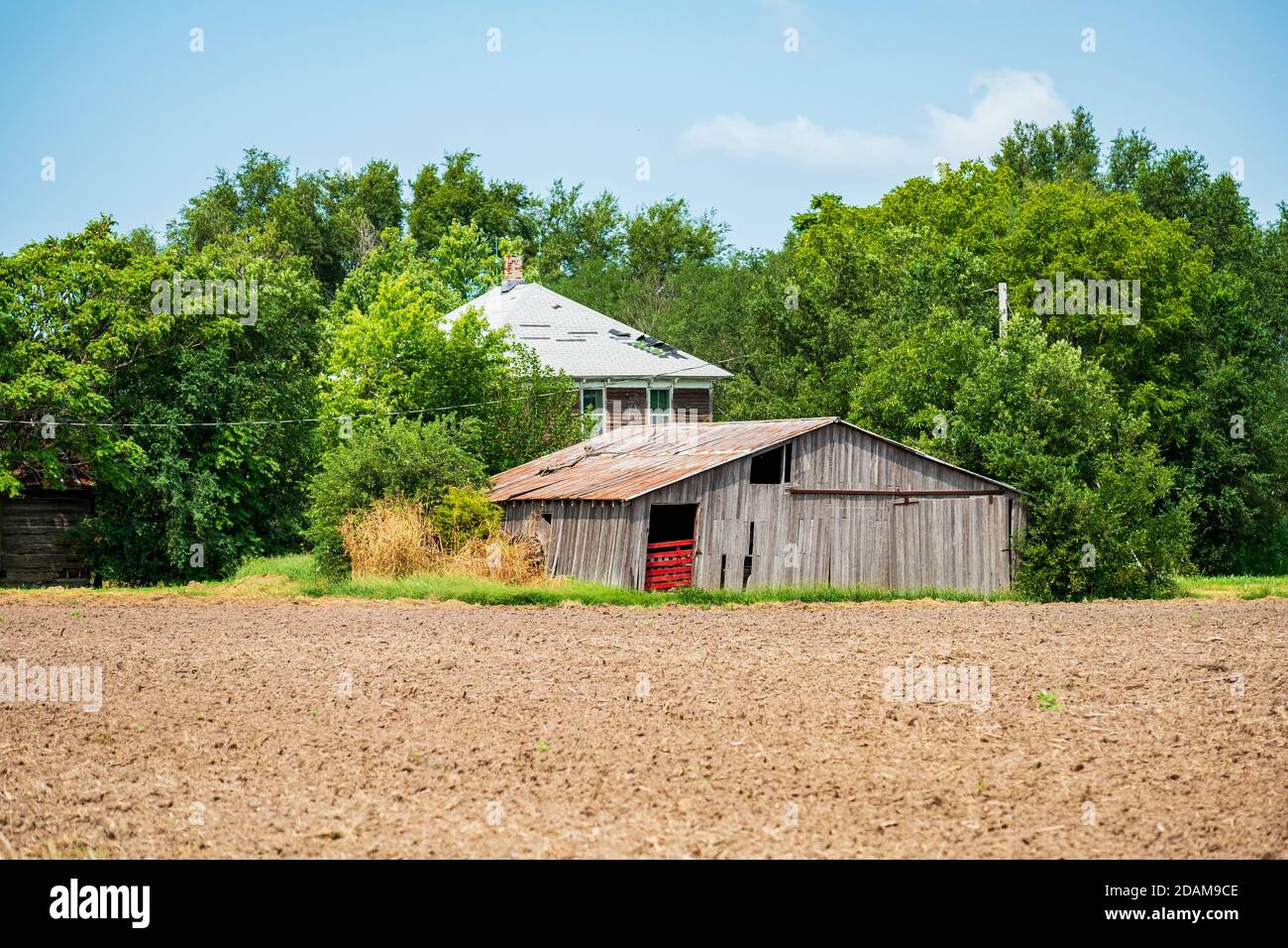 Fienile in legno o edificio agricolo dilapidati, e una vecchia casa colonica abbandonata in campagna accanto ad un campo arato in Kansas, Stati Uniti. Foto Stock