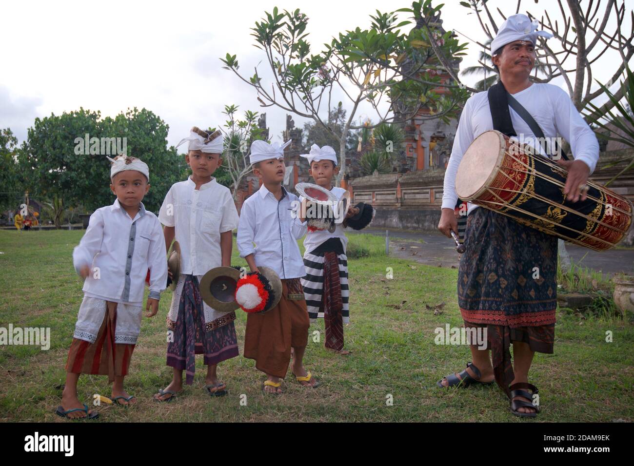 Ragazzi balinesi in abbigliamento festivo e un uomo bainese con un tamburo per un evento tempio durante Galungan, vicino a Ubud, Bali, Indonesia Foto Stock