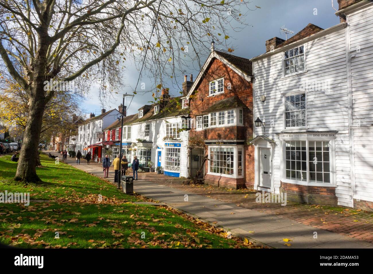 Le persone passeggiano lungo l'ampio marciapiede di Tenterden High Street in una soleggiata giornata autunnale, Kent, Regno Unito Foto Stock