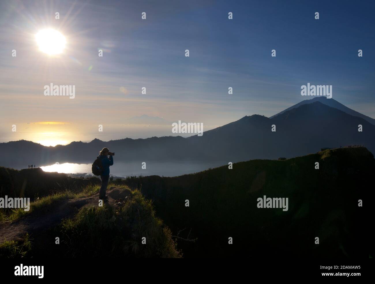 Fotografo che scatta una fotografia dal bordo della caldera del Monte Batur all'alba, Bali, Indonesia. Lago Batur sotto. Foto Stock