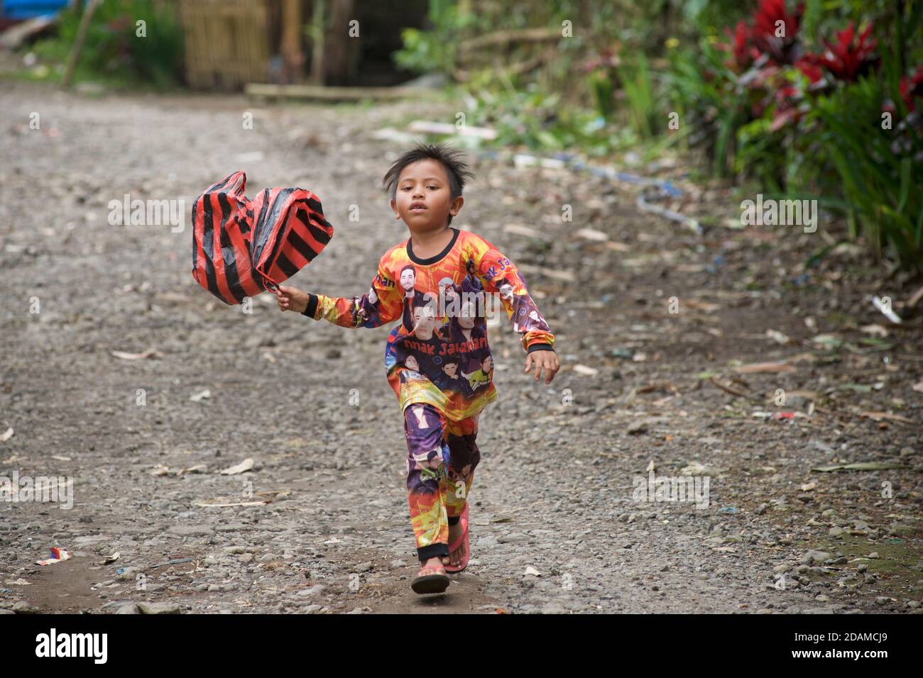 Ragazzo indonesiano che tira un pallone sgonfio come un aquilone, Pringgasela, Lombok, Indonesia. Foto Stock