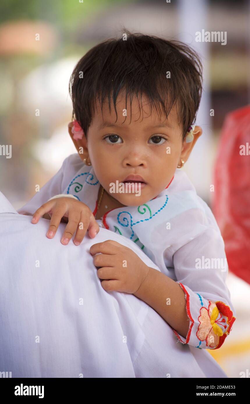 Ragazza balinese in abito festivo portato dal padre al tempio Sakenan, Bali, Indonesia per le feste galungane. Foto Stock