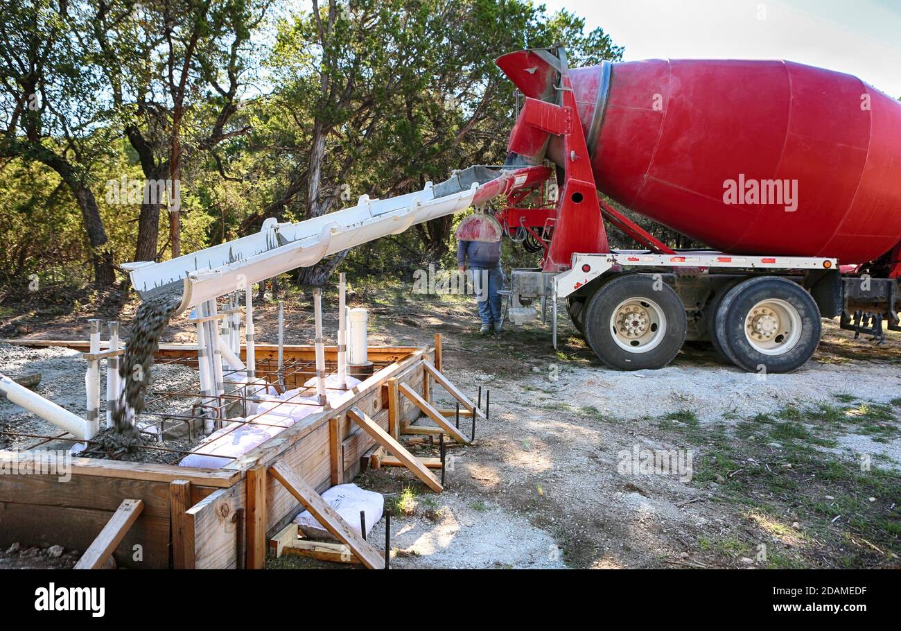 Grande betonaggio di camion che versa il calcestruzzo in una piccola casa d'acqua fondazione Foto Stock