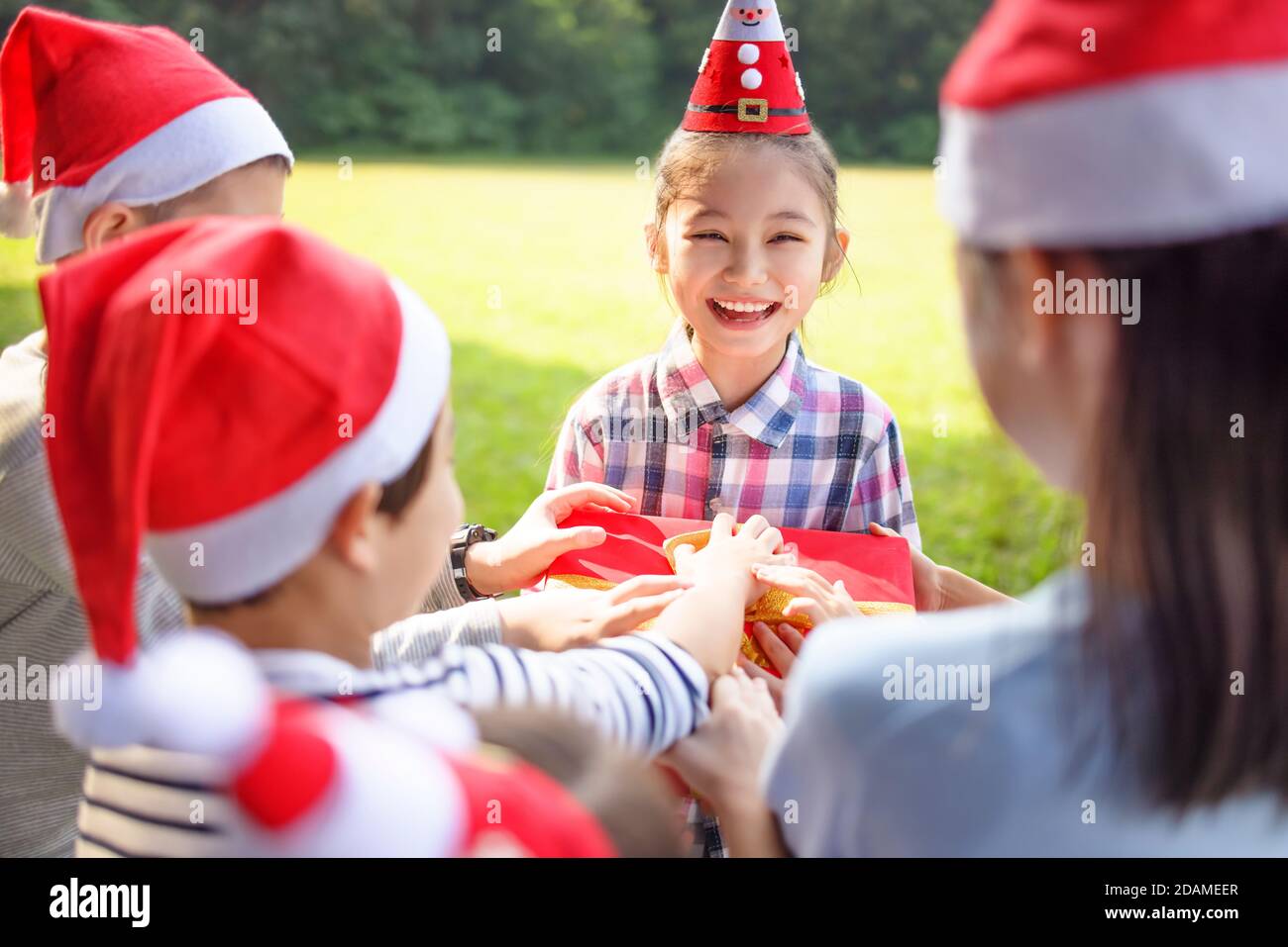 Felici i bambini nel cappello rosso di Santa e che tengono i regali di Natale Foto Stock
