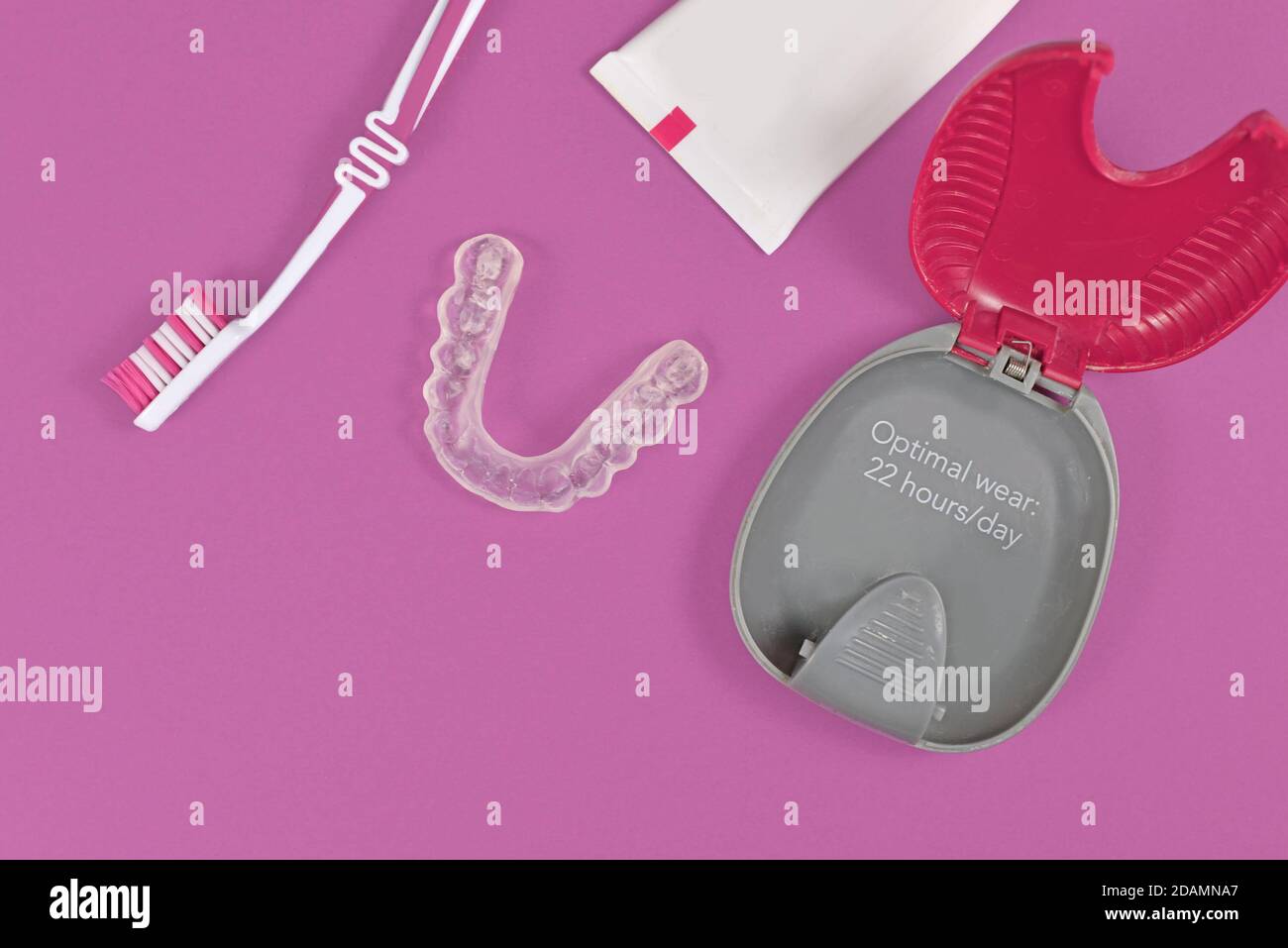 Protezioni per denti trasparenti personalizzate allineatori trasparenti per ganasce inferiori con custodia, spazzola per denti e pasta su sfondo rosa Foto Stock