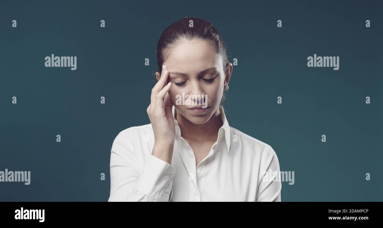 Giovane donna professionista che tocca i suoi templi, soffre di mal di testa Foto Stock