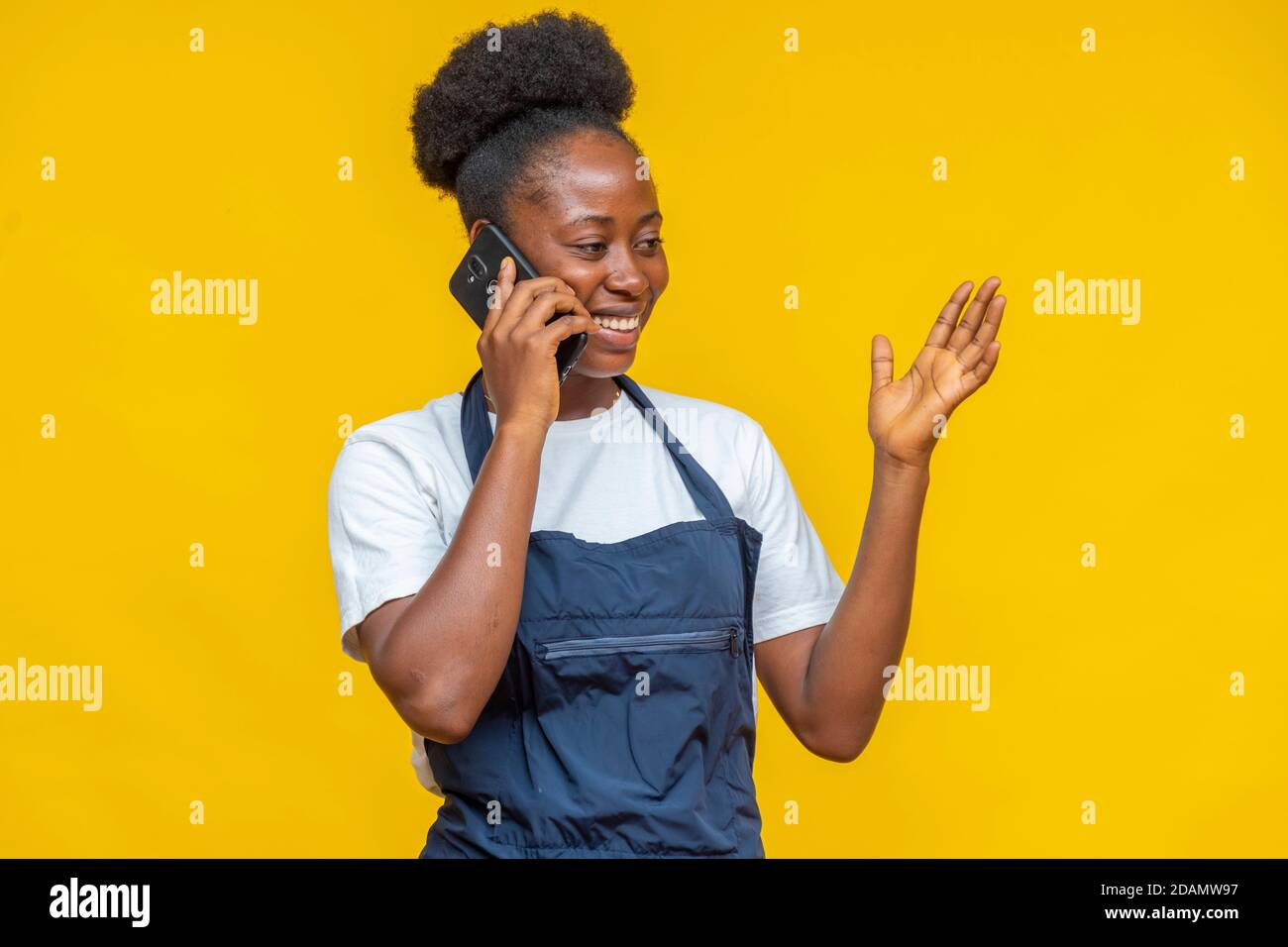 donna africana che indossa un grembiule che effettua una telefonata Foto Stock
