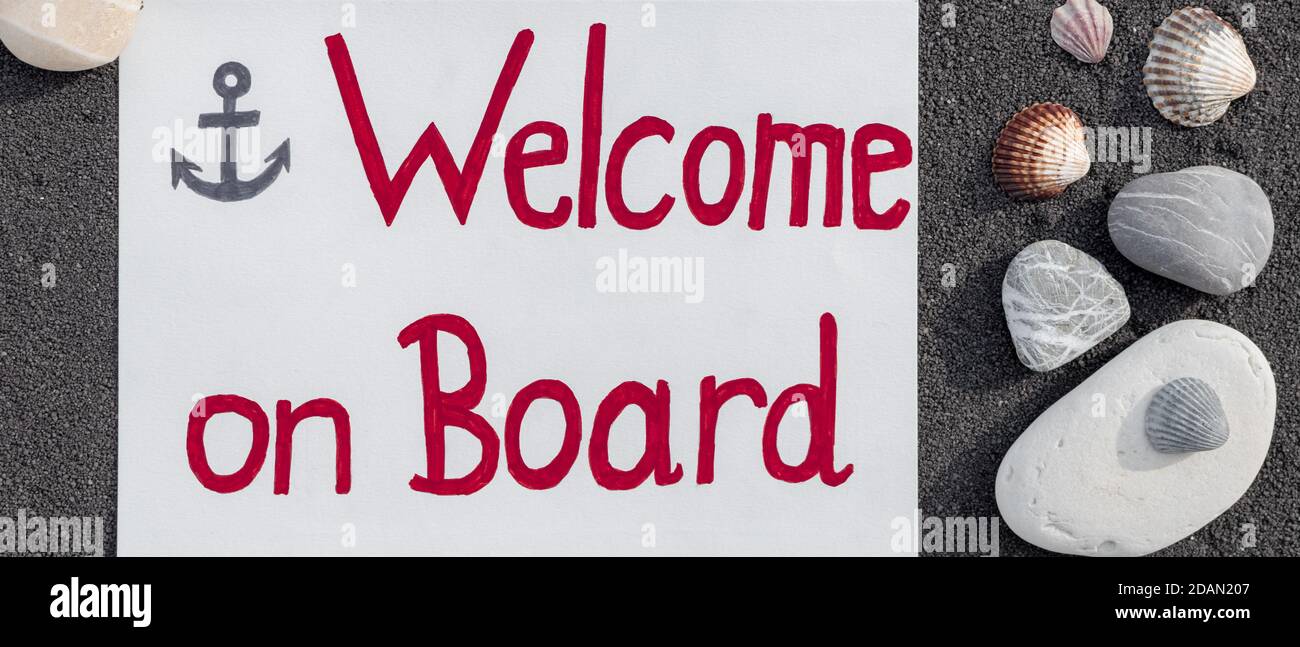Messaggio di benvenuto a bordo su sfondo di sabbia nera con ciottoli e conchiglie. Foto Stock