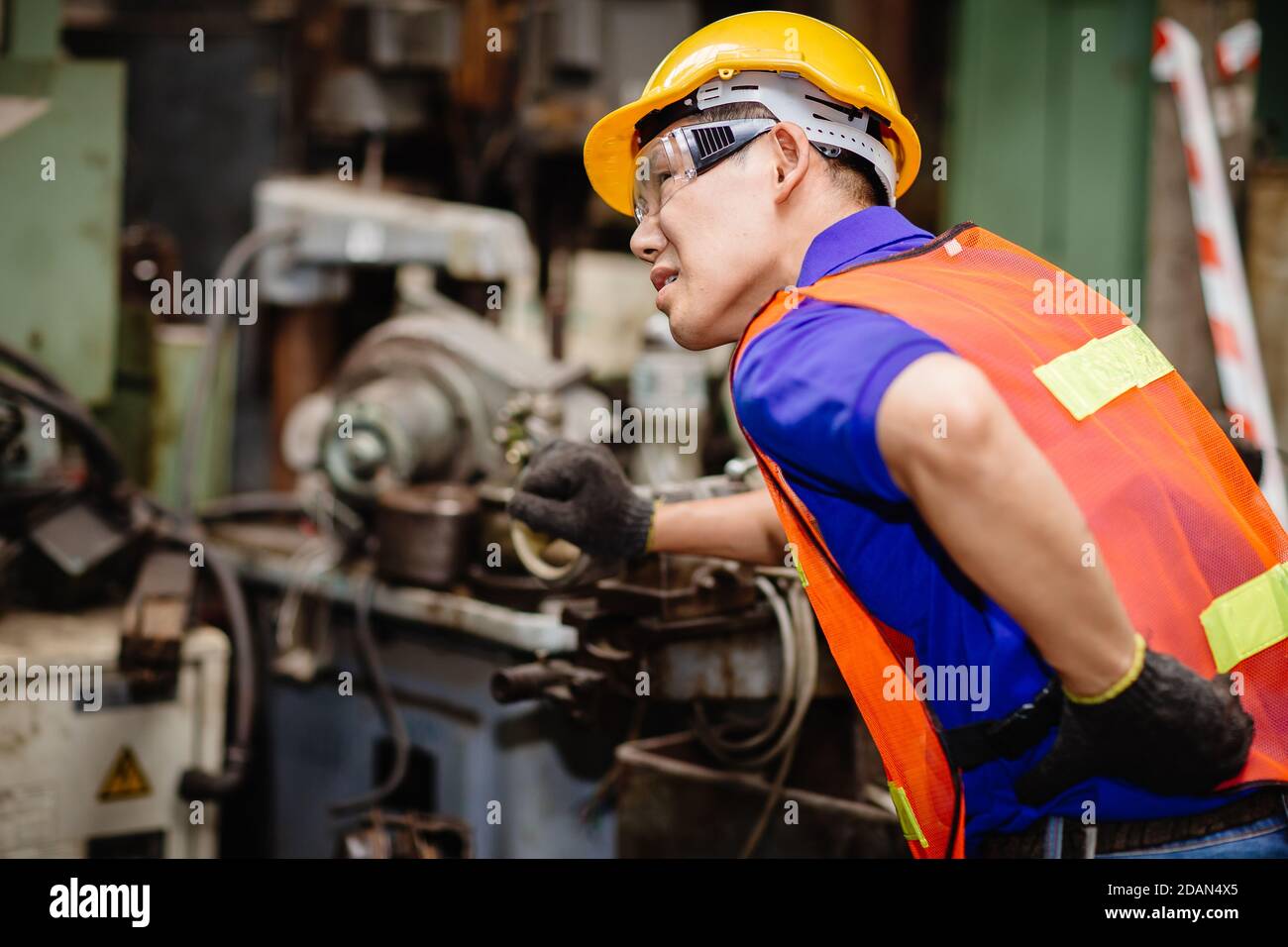 I lavoratori asiatici che lavorano sodo nelle fabbriche industriali soffrono di dolore alla schiena durante il lavoro sulle macchine. Foto Stock