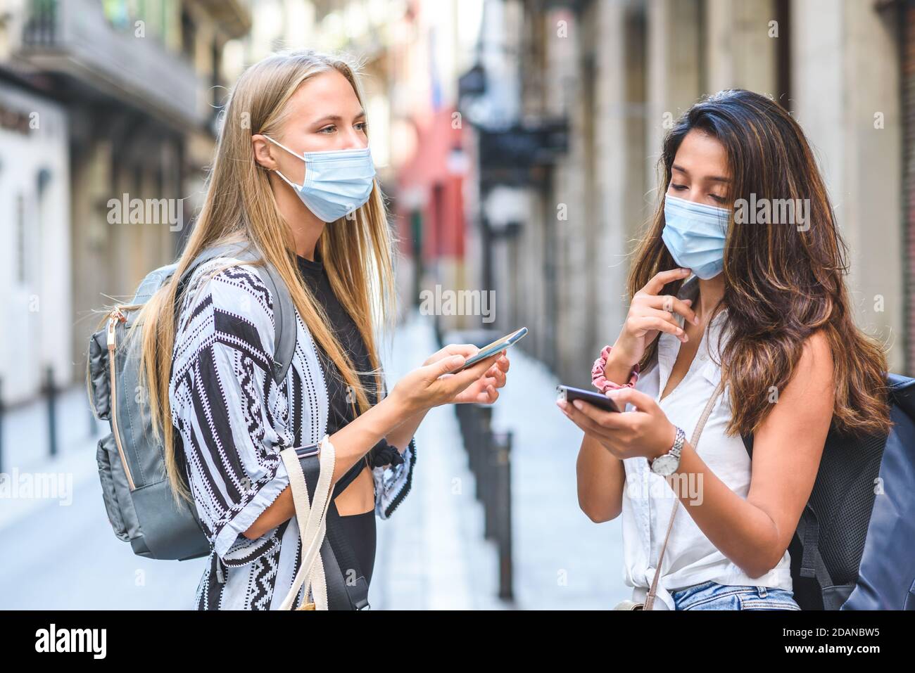 viaggiatori asiatici e caucasici con zaini sulla strada e alla ricerca di informazioni sui loro telefoni Foto Stock