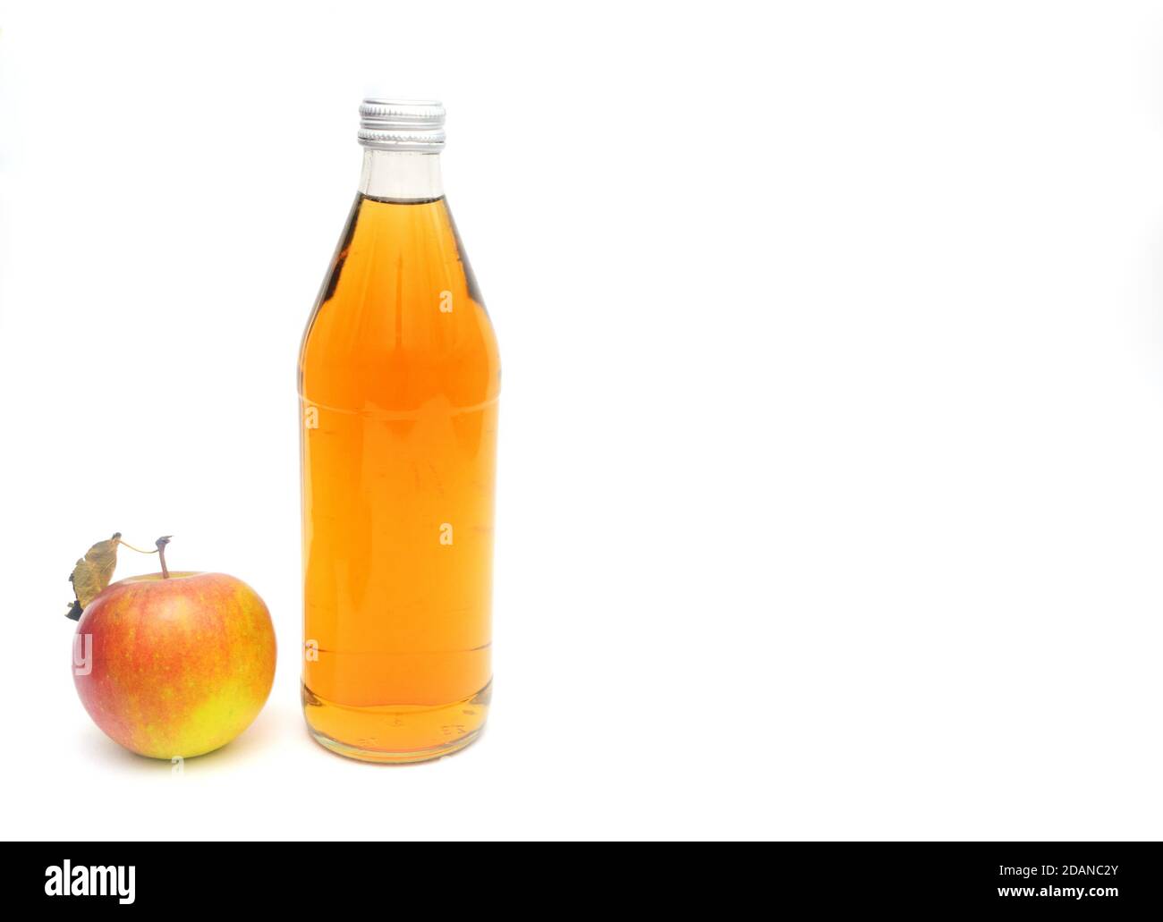 Una mela intera con foglia e una bottiglia di aceto di sidro di mele. Foto Stock