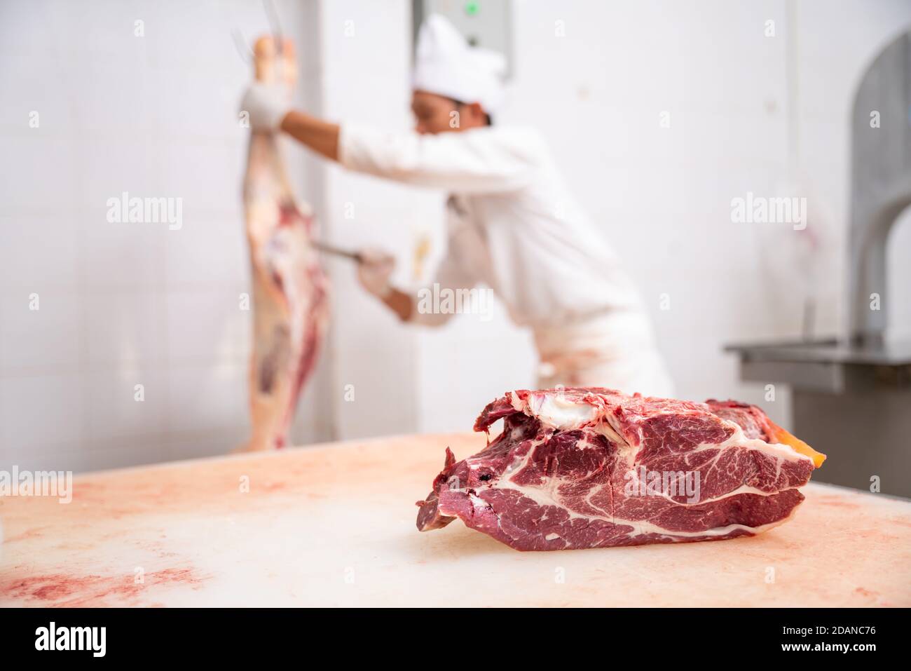 L'industria della carne, macellaio ha tagliato le carni grezze appese nel deposito freddo. Stattelle tagliate e impiccate al gancio nel macello, manzo Wagyu Foto Stock