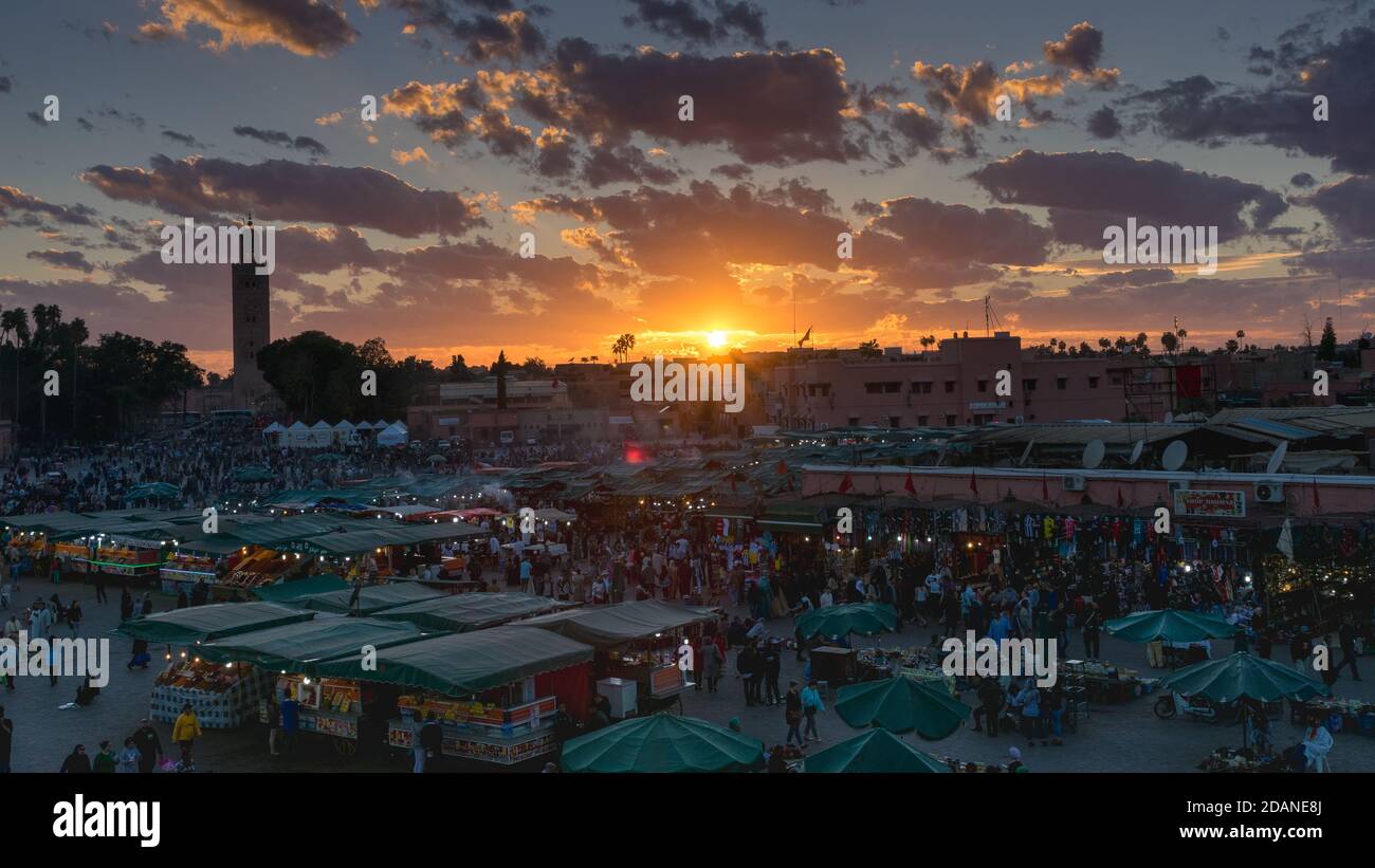 Piazza Yamaa el Fna con i suoi mercati e la folla di persone e la torre della moschea sullo sfondo, al tramonto. Concetto di viaggio. Marrakech, Marocco Foto Stock