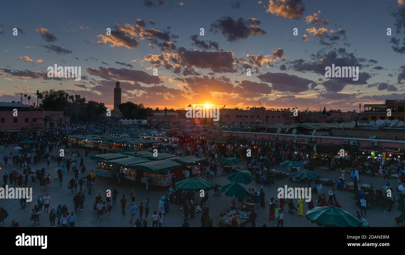 Piazza Yamaa el Fna con i suoi mercati e la folla di persone e la torre della moschea sullo sfondo, al tramonto. Concetto di viaggio. Marrakech, Marocco Foto Stock
