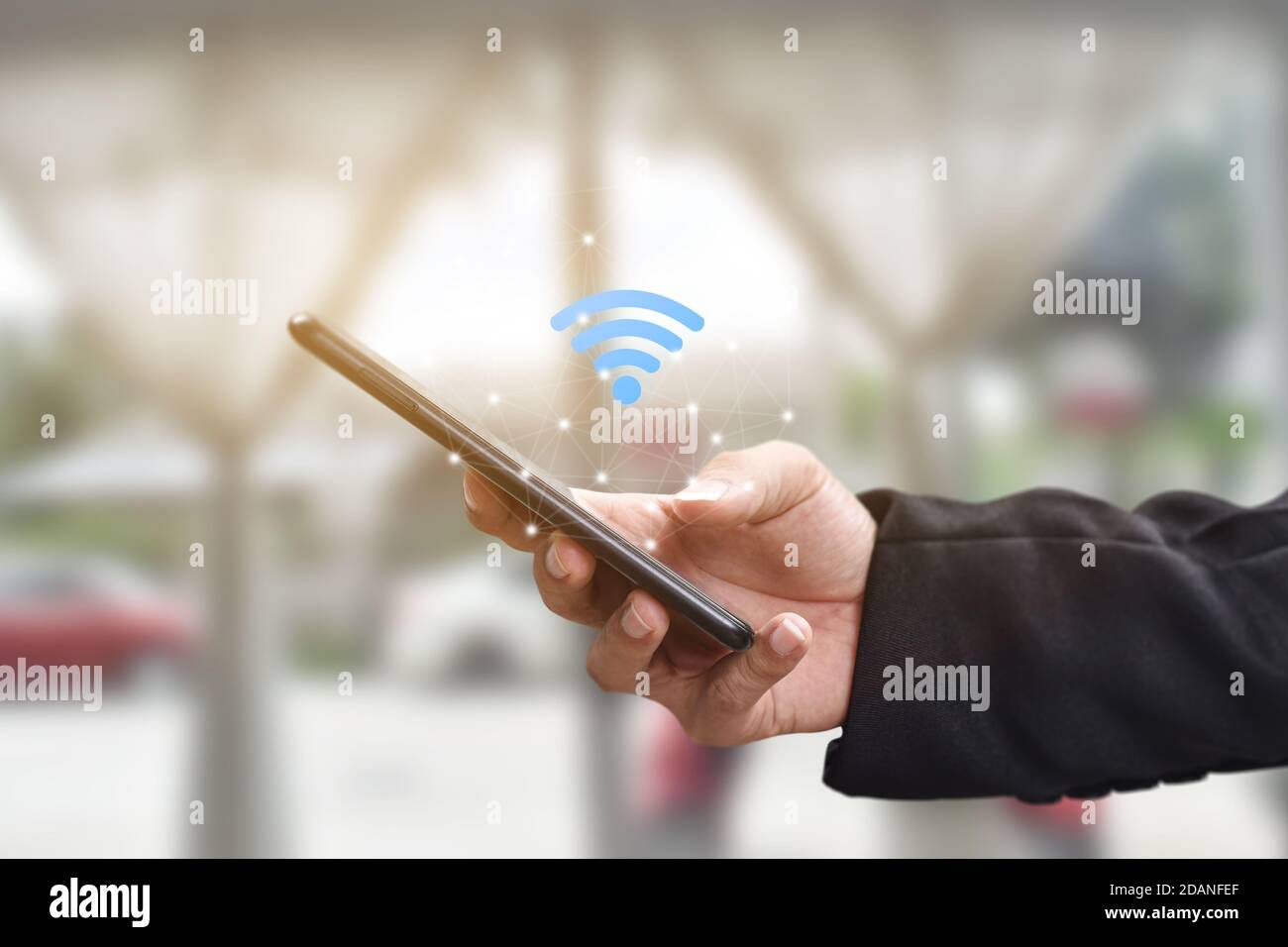 Tenere la mano utilizzando lo smartphone mobile con l'icona wifi. Idea per il social network di comunicazione aziendale. Foto Stock
