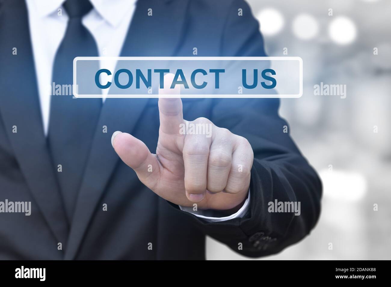 mano di uomo d'affari premendo un pulsante di contatto su blur bokeh luci di sfondo. Foto Stock