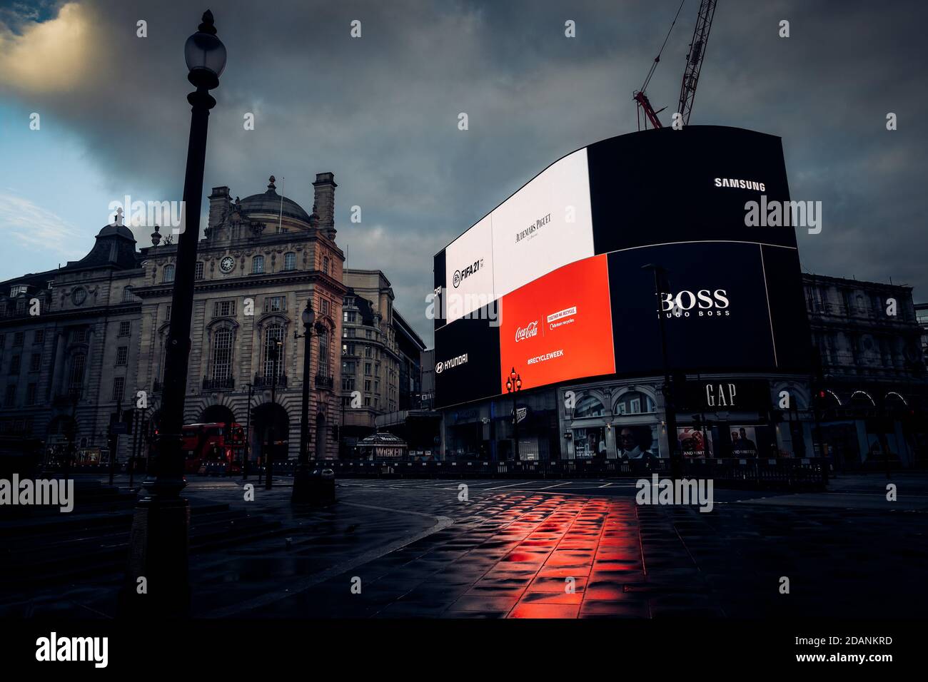 Al mattino presto in Lockdown Piccadilly Circus con nuvole scure nel cielo, Picadilly Circus segno neon illuminando con un riflesso rosso dal Coca- Foto Stock