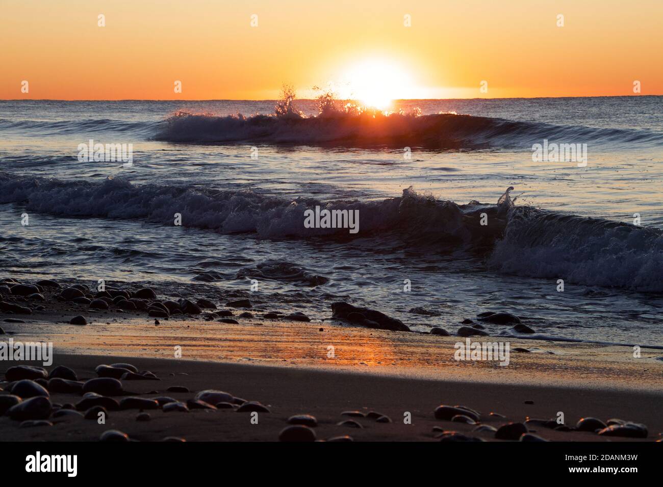L'onda spruzzi l'orizzonte all'alba arancione Foto Stock