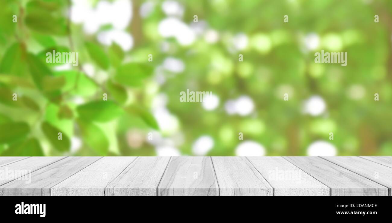 Piano vuoto in legno bianco con sfondo verde sfocato bokeh. Per la visualizzazione o il montaggio di pubblicità prodotto. Foto Stock
