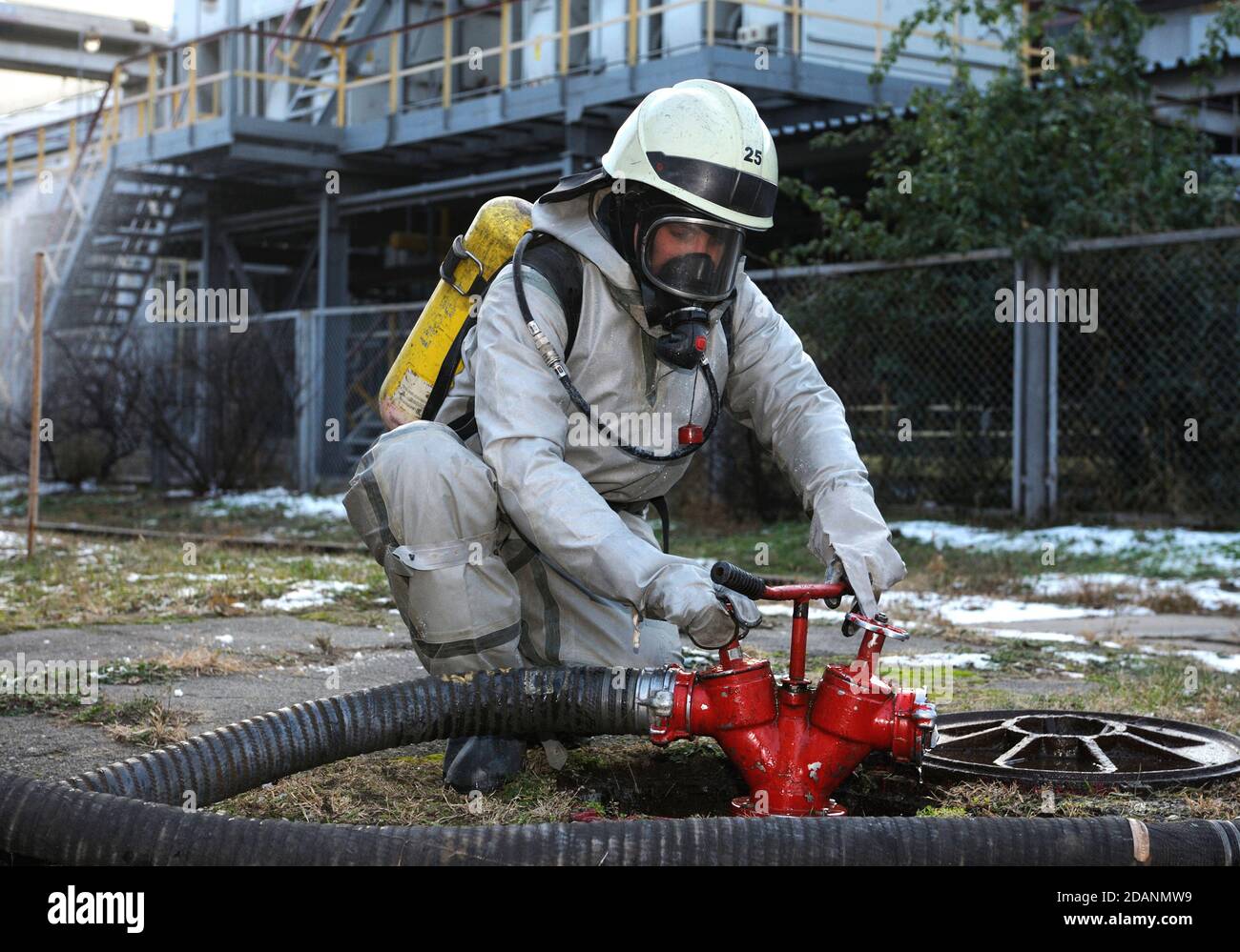 Formazione del team di soccorso sulla decontaminazione chimica: Soccorritore in un gruppo protettivo che gira una valvola di un idrante antincendio Foto Stock